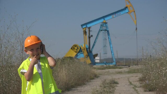 Little kid plays as engineer talking on phone near petrol oil extraction pump