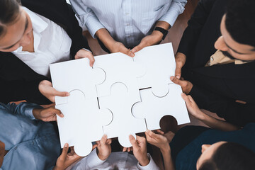 Diverse corporate officer workers collaborate in office, connecting puzzle pieces to represent...