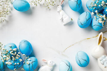 Easter holiday decorations with blue eggs and flowers on marble table. Top view. Flat lay.