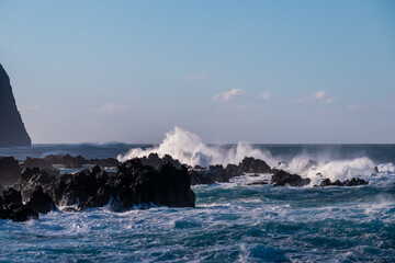 Strong waves smashing against jagged volcanic rocks on pristine coastline of coastal town Porto Moniz, Madeira island, Portugal, Europe. Powerful natural forces of majestic Atlantic Ocean. Seascape