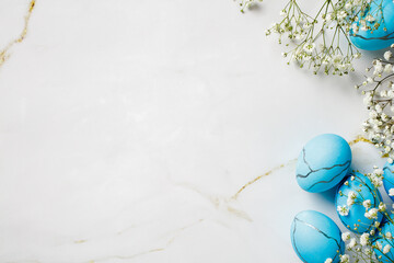 Blue delicate Easter eggs and flowers on a marble table. View from above
