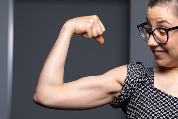 Confident Young Woman Flexing Biceps with a Proud Smile