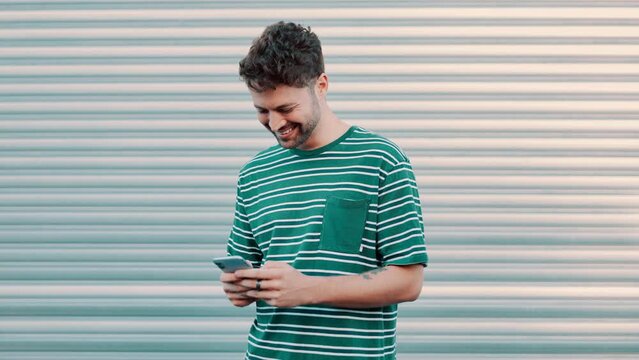 Man, phone and laughing for meme outdoors, smile and internet for comic on social media. Happy male person, app and online for funny blog or website, streaming comedy and humor by wall background
