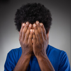 individual hiding face, embodying emotions of sadness or shame