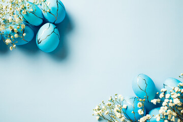 Elegant Easter eggs with white flowers on pastel blue background. Flat lay, top view, copy space.
