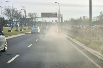 Niebezpieczny dym wylatuje z tłumika samochodu jadącego w korku w mieście. Zadyma - obrazy, fototapety, plakaty