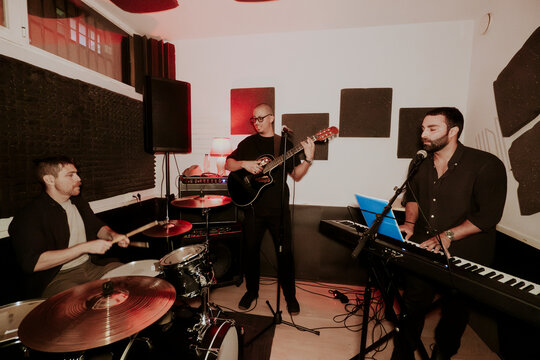 Intense performance by male music trio in a studio