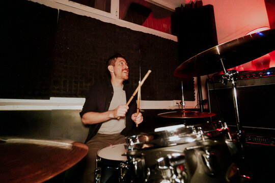 Drummer playing in a band looking away from camera