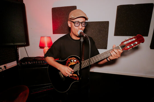 Male musician playing acoustic guitar on studio