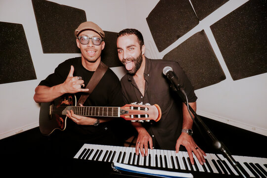Two male musicians with guitar and keyboard in studio