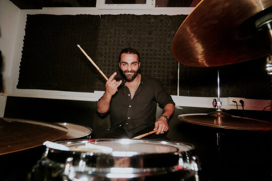 Smiling drummer with drumsticks in band rehearsal studio