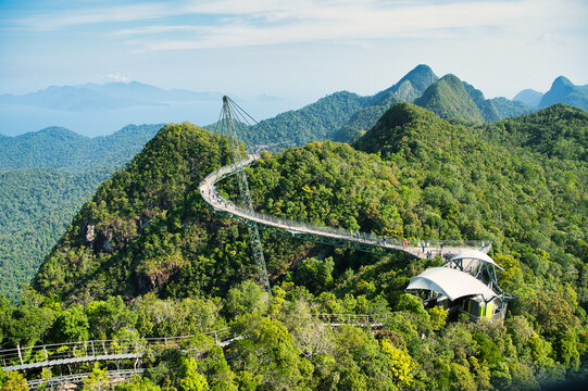 The Langkawi Sky Bridge, set against a backdrop of lush mountains and blue skies, offers breathtaking views over the Malaysian archipelago