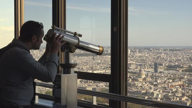 Tourist watching Paris city panorama from an observation telescope