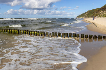 Scenic view of wooden breakwater with Green algae in foaming water of Baltic Sea, Miedzyzdroje,...