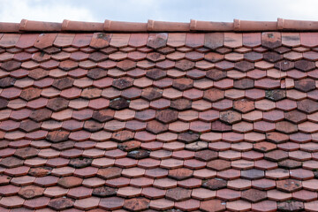 Fototapeta premium A close-up of a textured red tiled roof showcases traditional craftsmanship and architectural detail symbolizing durability and long-lasting quality in construction.