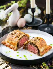 Fresh puff pastry bun with beef meat and spinach on marble table with easter decoration. Happy Easter food, top view
