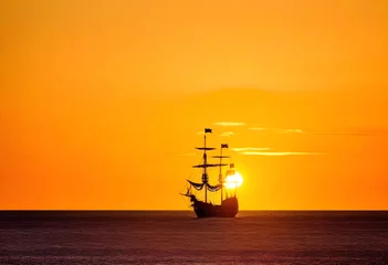 Fotobehang Pirate ship at the open sea at the sunset with copy space © Umer