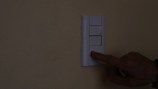 El hombre prende la luz de su hogar con el interruptor de luz presionando con el dedo en el pulsador,  permitiendo que el circuito el&eacute;ctirco se ponga en funcionamiento