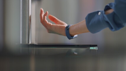 Woman hand swiping smartwatch on sensor panel electronic turnstile close up.