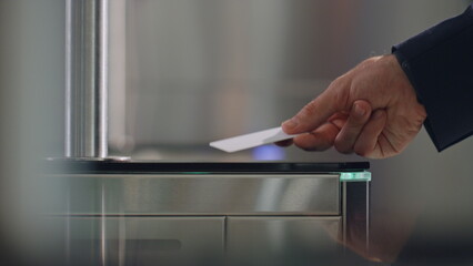 Businessman hand applying card unlocking gate at office entrance close up.