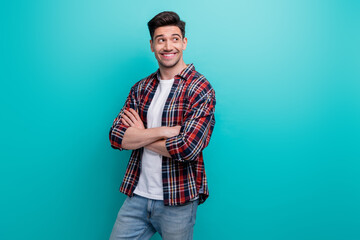 Photo of good mood dreamy man dressed plaid shirt arms folded looking empty space isolated turquoise blue color background