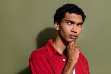 Photo of doubtful uncertain guy wear red shirt arm chin looking empty space isolated khaki color background