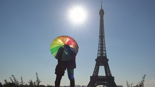 Lovers couple silhouette under multicolor umbrella near Eiffel Tower