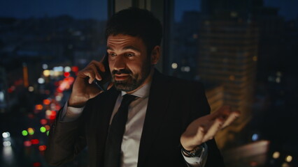 Emotional businessman shouting phone standing office late evening close up.