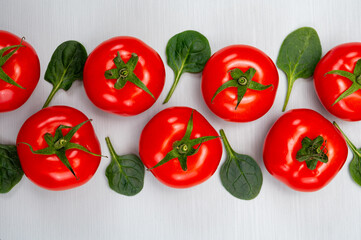 Food ornament, Red ripe tasty Dutch tomatoes and spinach leaves, vegetables background top view close up copy space