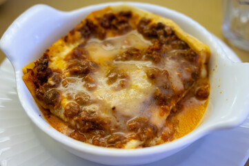 Traditional first course for lunch or dinner in Italy, lasagne Bolognese with beef meat and bechamel sauce served in Italian restaurant, Milan, Italy