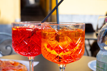 Aperol and Campari Spritz orange bitter long drink cocktails made with liqueur, prosecco sparkling wine, ice cubes and piece of orange, Milan, Italy