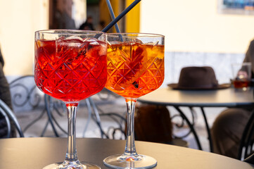 Aperol and Campari Spritz orange bitter long drink cocktails made with liqueur, prosecco sparkling wine, ice cubes and piece of orange, Milan, Italy