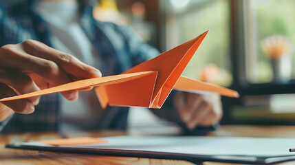 A person making a paper airplane, showing how to streamline processes in business - obrazy, fototapety, plakaty