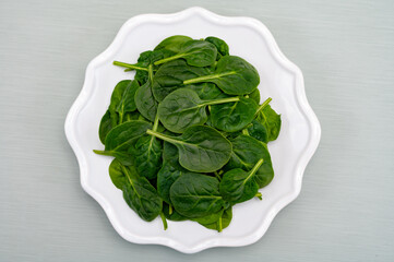 Fresh green baby Spinach leaves, diet and health concept, weight loss, spinach on ceramic plate, copy space