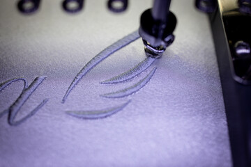 Embroidery wings with grey thread on a white satin robe for the bride.