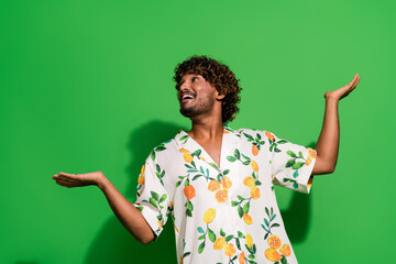 Photo of excited funky arabian man wear print shirt showing arms scales looking empty space...