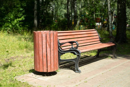 Shop in park. Bench and trash can made of wood. Forged metal in park furniture.