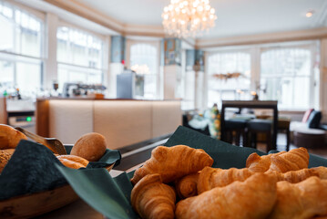 Closeup of freshly baked bread and croissants in a basket with a dark green napkin, set in a luxury...