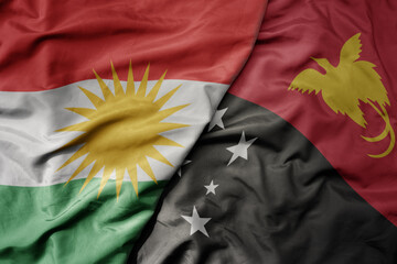 big waving national colorful flag of Papua New Guinea and national flag of kurdistan.
