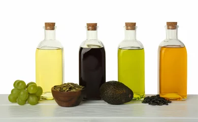 Fotobehang Vegetable fats. Bottles of different cooking oils and ingredients on wooden table against white background © New Africa