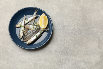 Fresh raw sprats, green onion and cut lemon on grey table, top view. Space for text