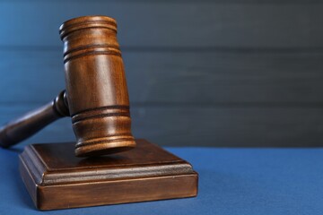 Wooden gavel on blue table, closeup. Space for text