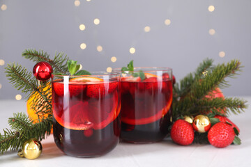 Aromatic Christmas Sangria in glasses and festive decor on white table, closeup