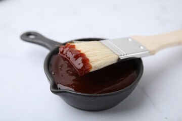 Marinade in gravy boat and basting brush on white table, closeup