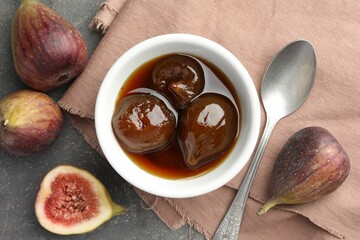 Bowl of tasty sweet jam, fresh figs and spoon on grey table, flat lay