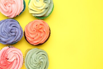 Delicious cupcake with bright cream on yellow background, flat lay. Space for text
