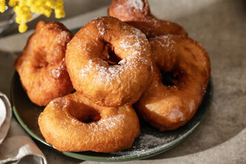 Delicious homemade crumpets or fried donuts sprinkled with powdered sugar on textured table...