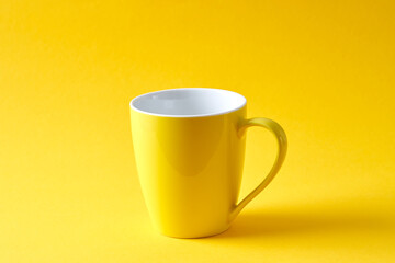Empty yellow mug on yellow background.