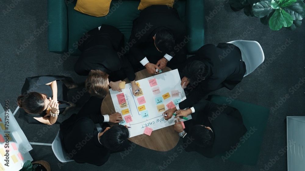 Poster close up of professional business team hands writing and putting sticky note on scrum task board. to