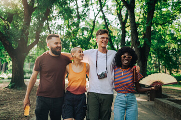 Happy interracial friends hugging and walking in a park on summer vacation.